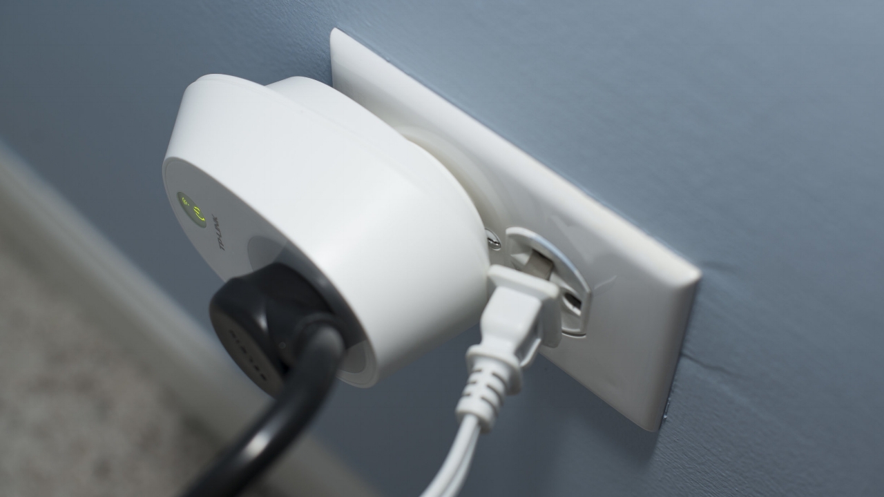 Power outlets with a large TP Link smart plug next to a standard power plug, the standard power plug is dislodged
