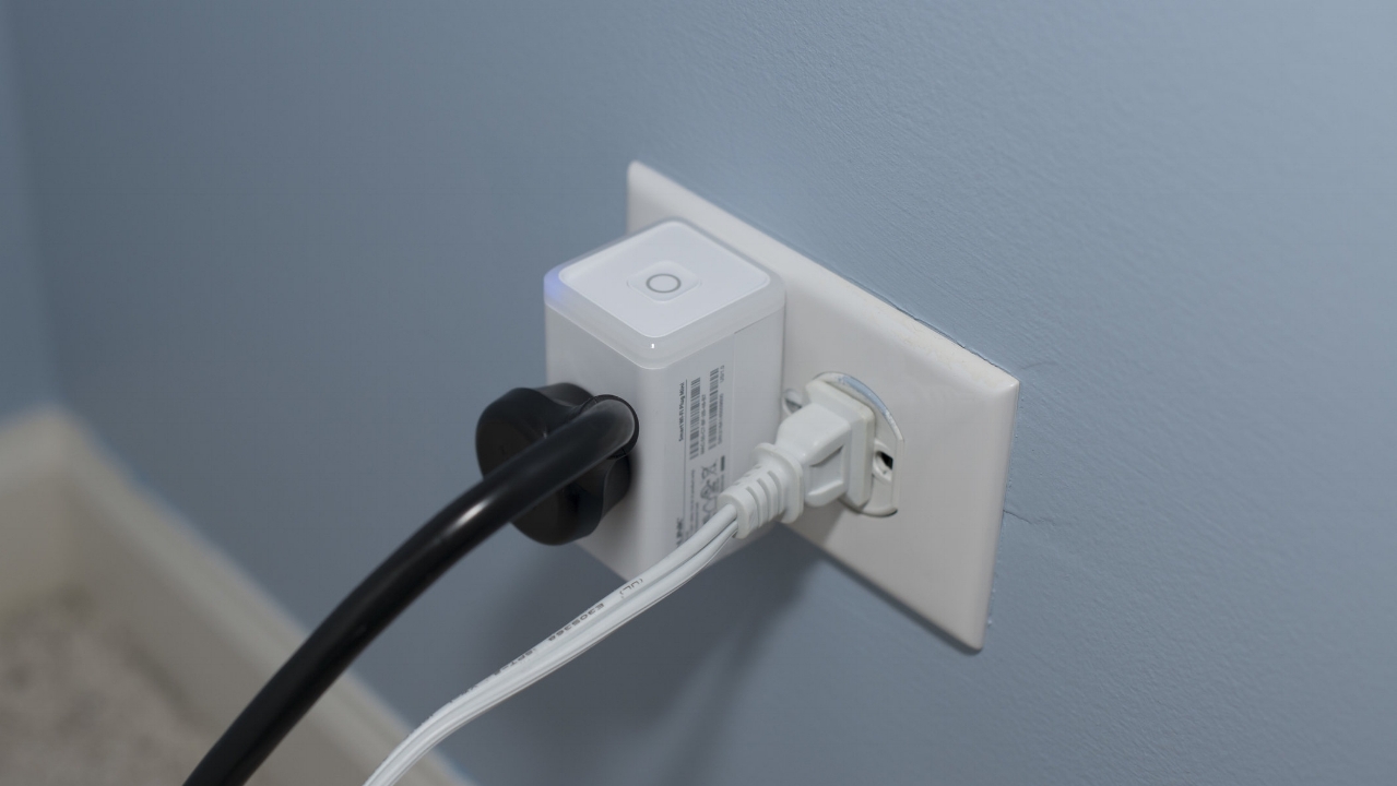 Power outlets with a small TP Link smart plug next to a standard power plug, no plugs are displaced